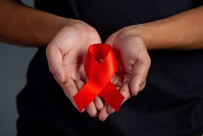 woman-hand-holding-red-ribbon-hiv-awareness-concept-world-aids-day-world-sexual-health-day